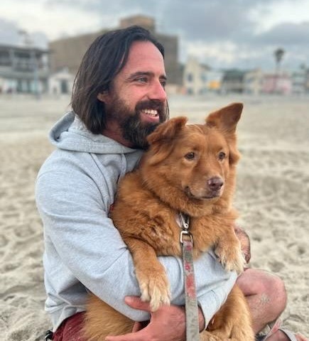 Philip Berry holding Goldilocks on the beach at sunset in Mission Beach, San Diego